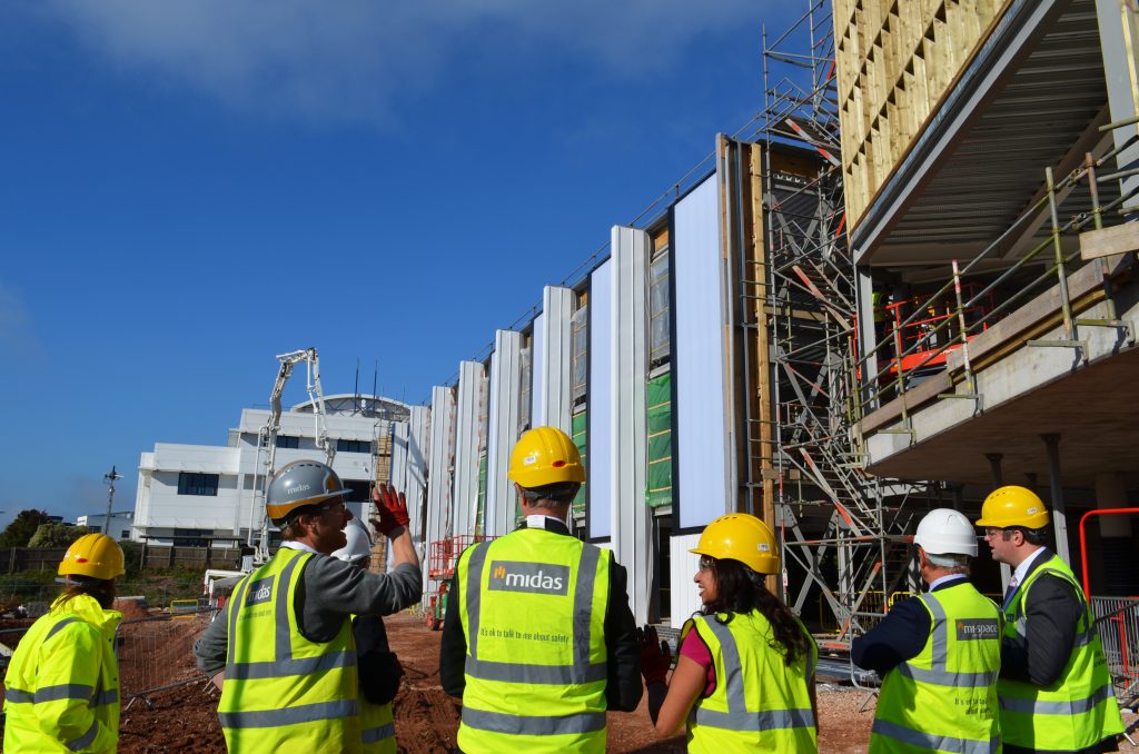 A group of people in hi-vis jackets in front of a partially constructed building